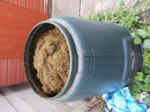 Composteur de jardin à mi-ombre avec matières sèches et fraîches pour relancer un compost trop sec en été.